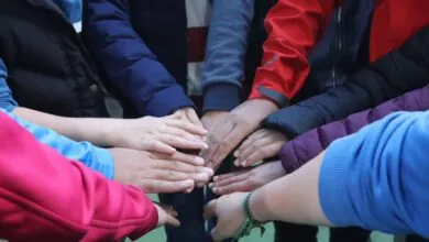 A group of people holding their hands in the middle.