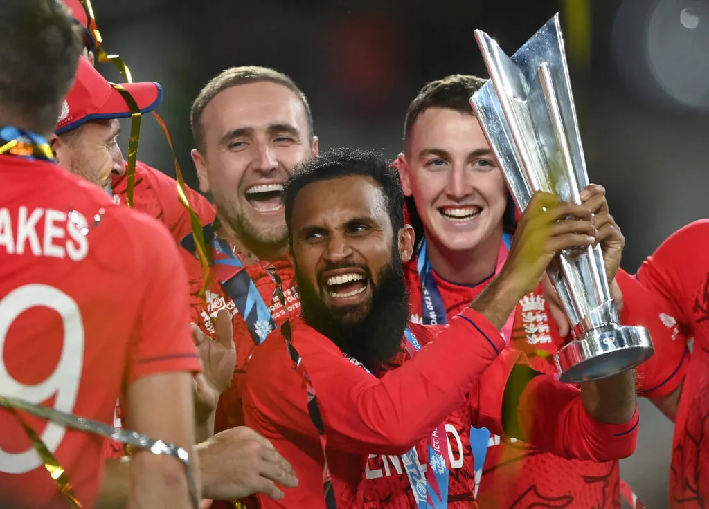 Adil Rashid is pictured with his English team mates celebrate with the ICC Men's T20 World Cup Trophy after winning the ICC Men's T20 World Cup Final match between Pakistan and England at the Melbourne Cricket Ground on November 13, 2022 in Melbourne, Australia. Photo credit: Quinn Rooney/Getty Images